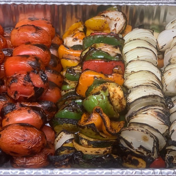 Grilled tomatoes, bell peppers, and onions in a foil pan, ready to serve at Noras Kabob.