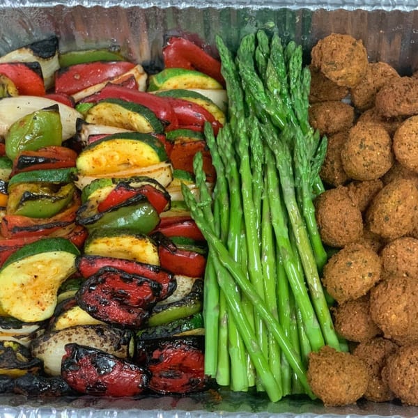 A catering tray with grilled vegetables, asparagus, and falafel from Noras Kabob.