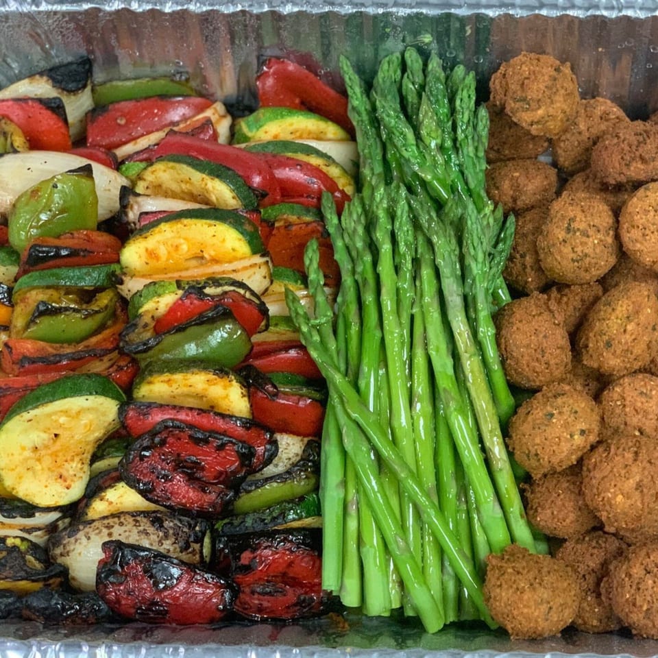 A catering tray with grilled vegetables, asparagus, and falafel from Noras Kabob.