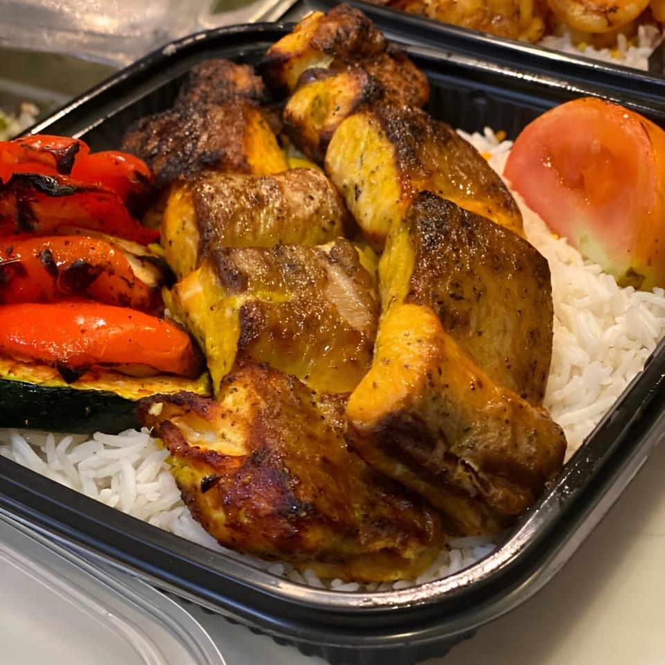 Nora's Kabob chicken and vegetable platter with rice, grilled peppers, zucchini, and tomato.